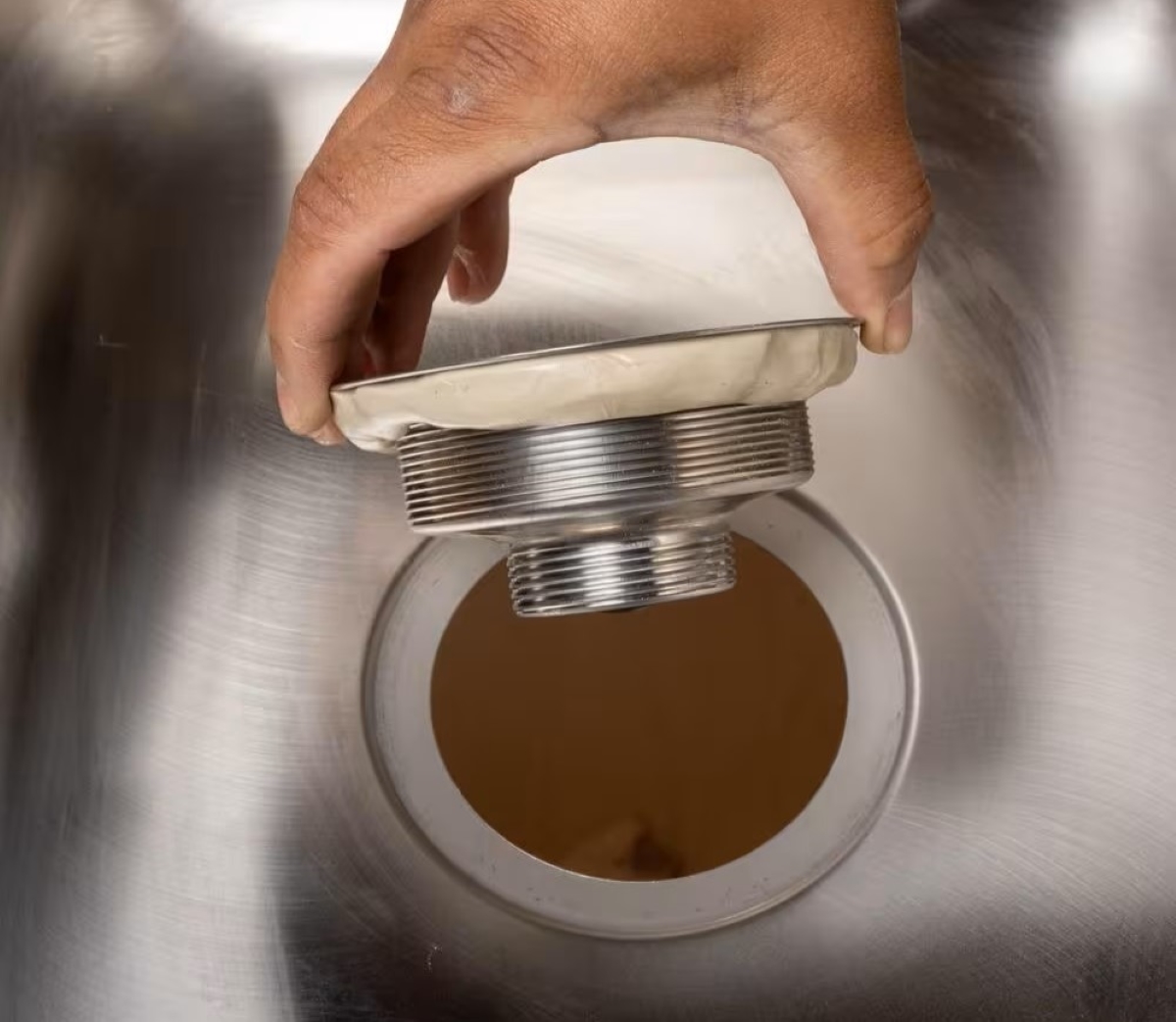 Person holding sink flange with putty.