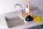 A plunger and yellow rubber gloves on top of a clogged kitchen sink
