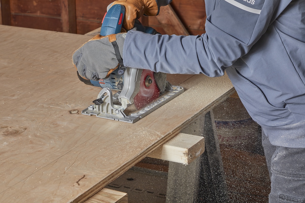 Woman uses a circular saw to make a rip cut on a sheet of plywood.