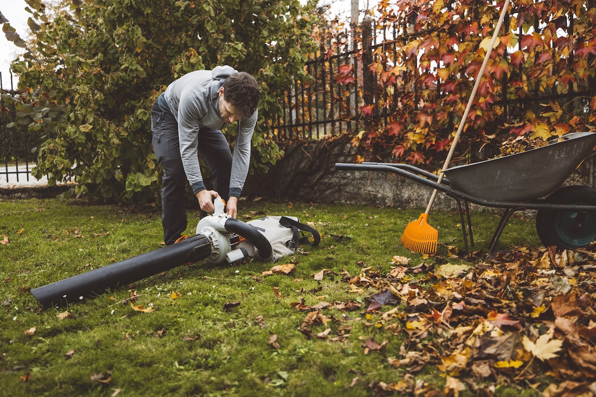 A man leans down to operate on a leaf blower