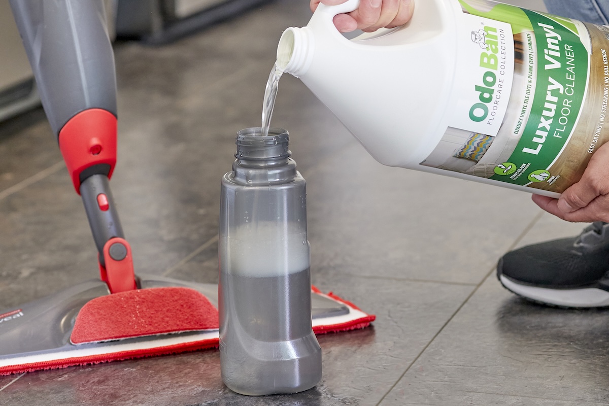 Person pours vinyl-safe cleaning product into a mop reservoir.