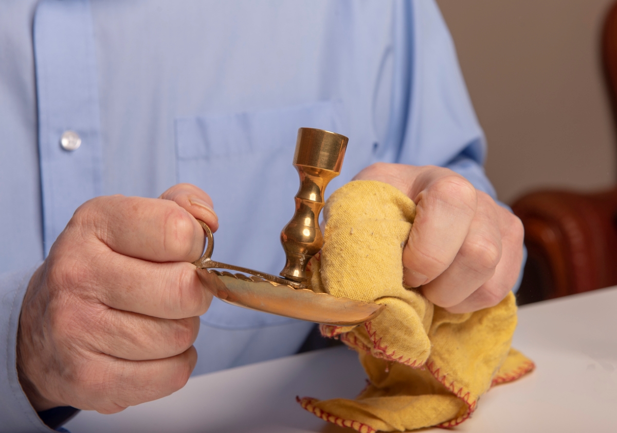 Man using microfiber towel to clean brass candle stick