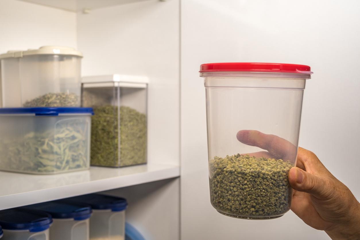 Hand taking thyme from shelf in number 5 plastic storage container