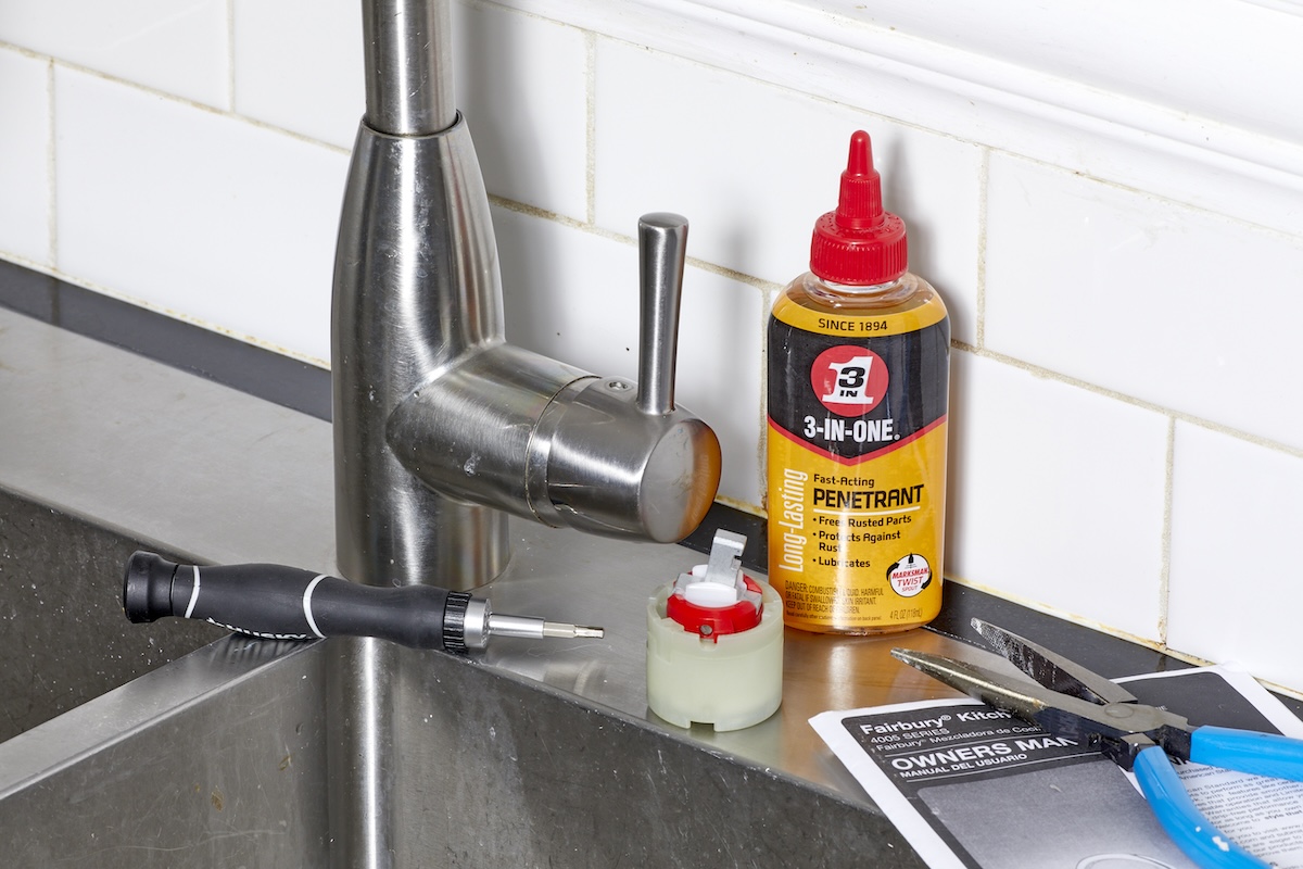 Kitchen sink and faucet plus materials for fixing the faucet, including penetrating oil, wrench, and other things.