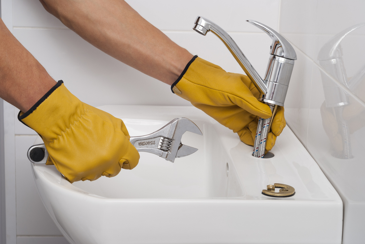 plumber installs a new faucet for a sink