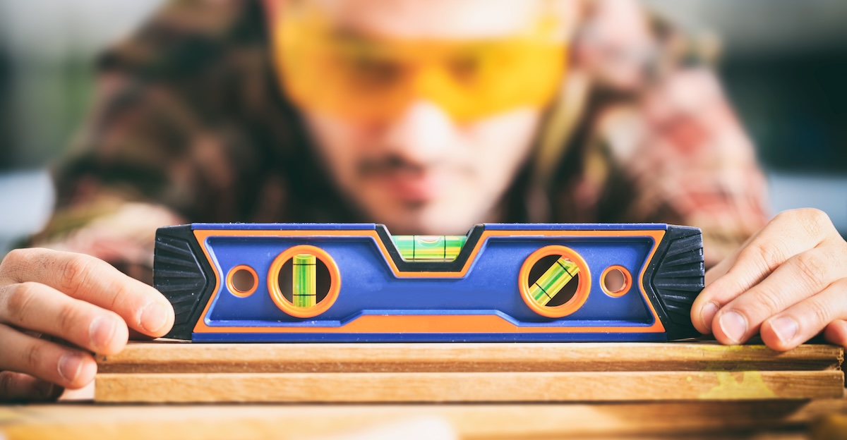 A carpenter checks a level by placing it on a flat surface.