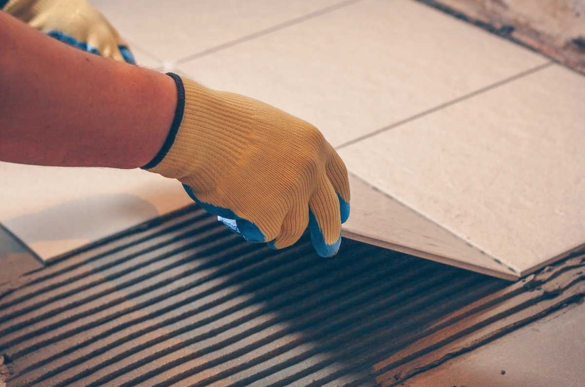 Man sets tiles on the floor into mortar.
