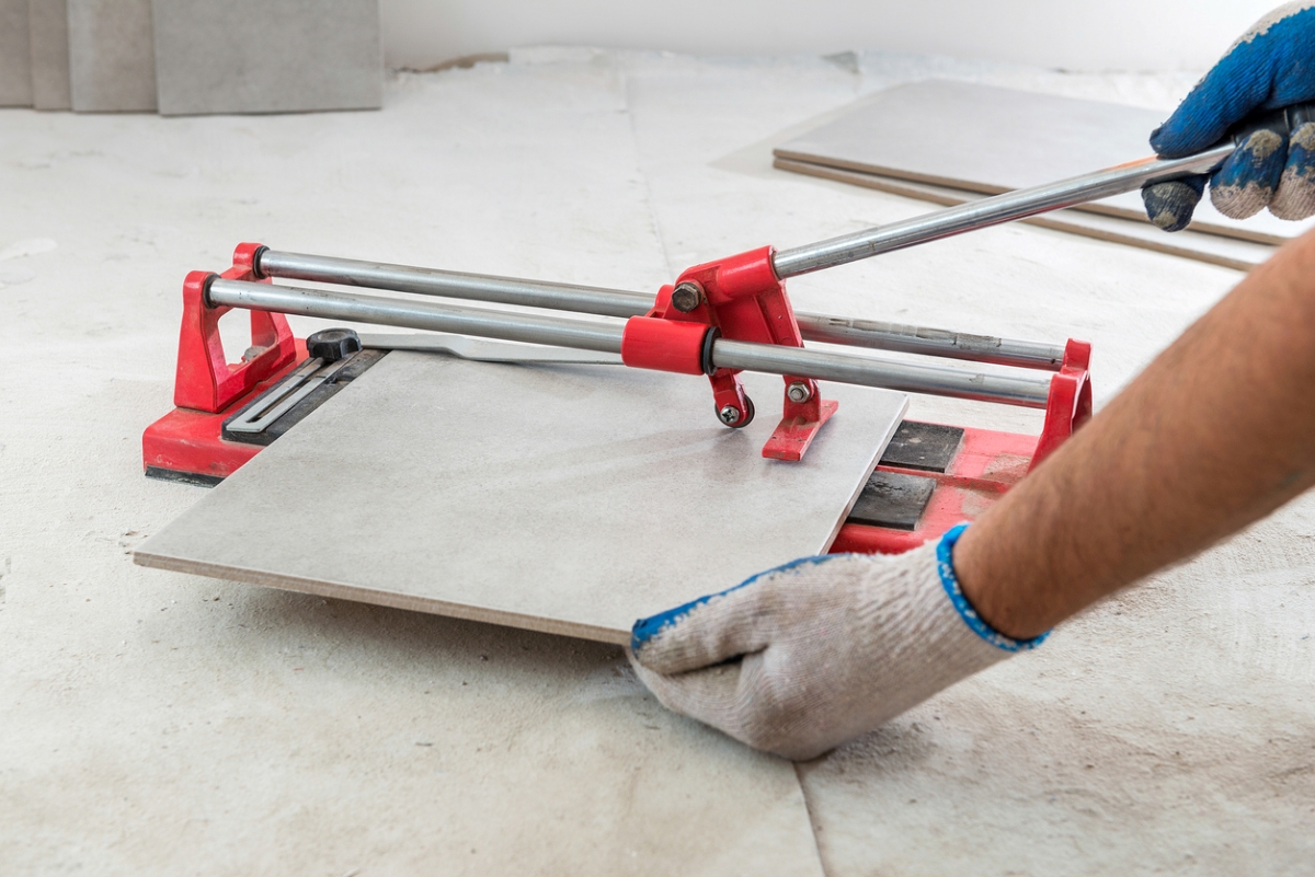 how to install ceramic tile - man using tile cutter