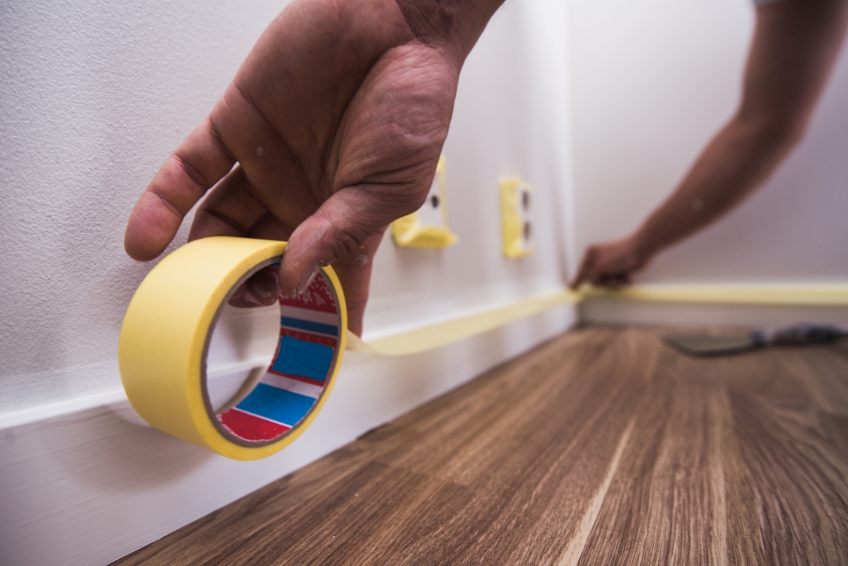 Person applying painters tape to wall trim