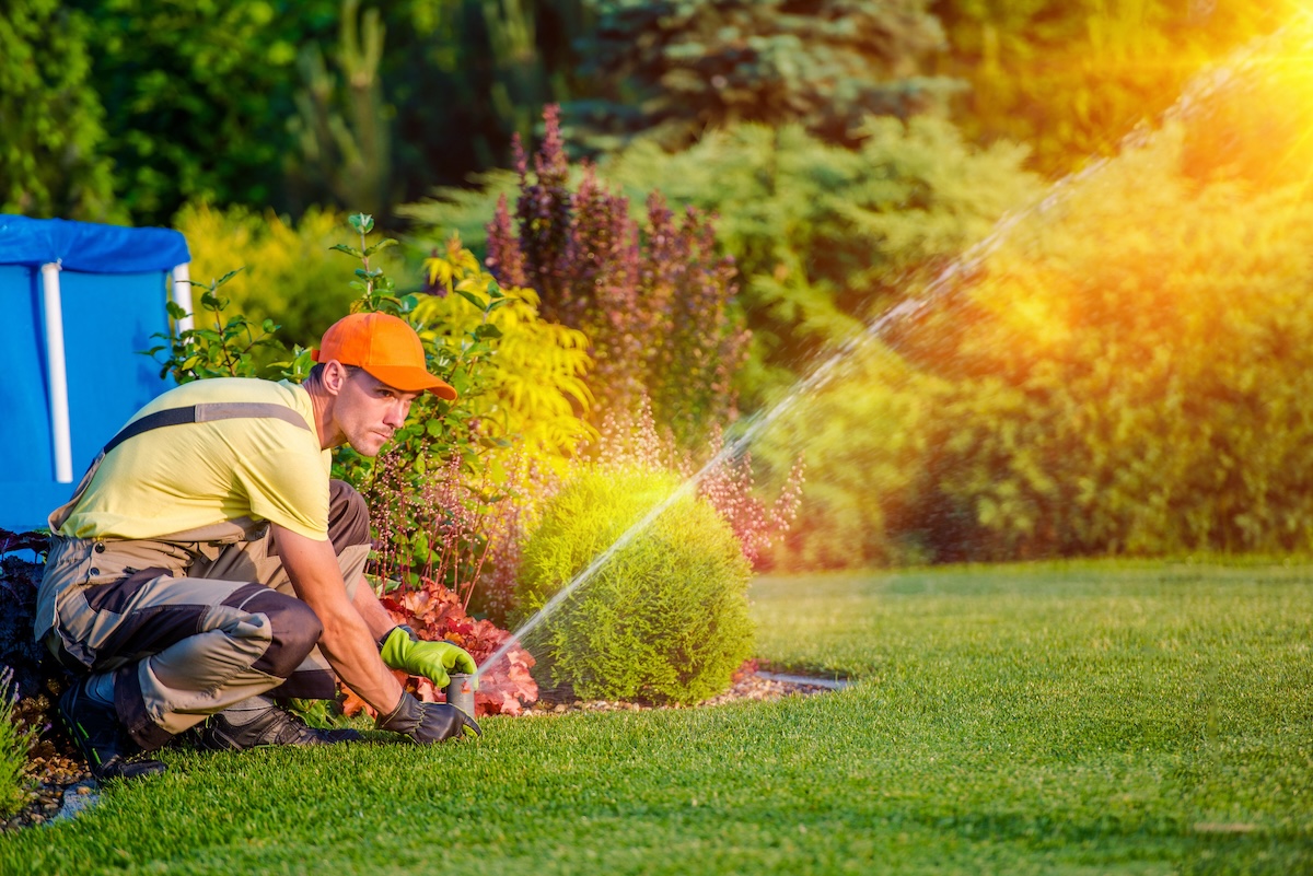 A professional maintenance worker repairs a sprinkler system.