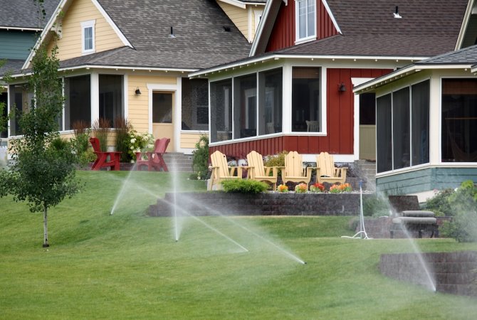 Water sprinklers irrigate the lawns of several bungalow homes.