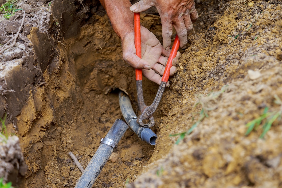 Using a wrench to repair an underground irrigation system.