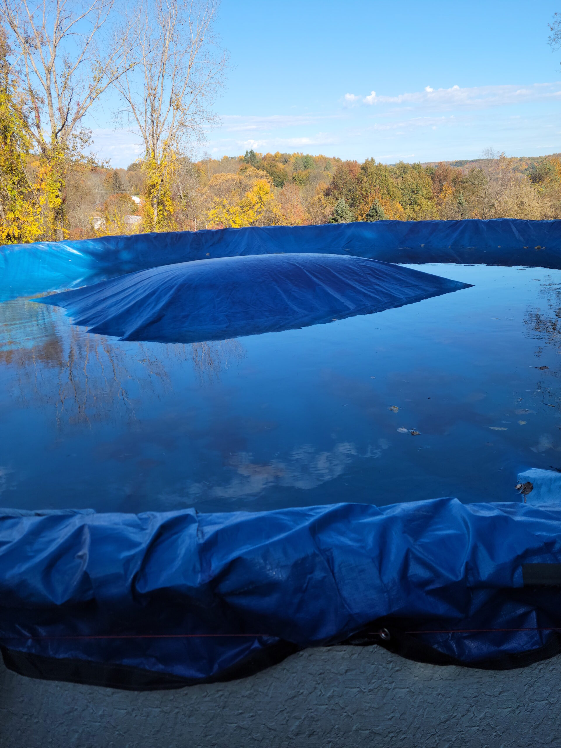 A round pool closed for the winter with pool pillow rising from beneath the cover.