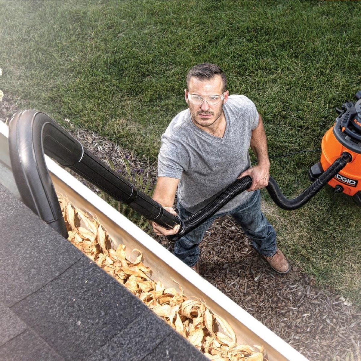 Man using vacuum to clean gutters.
