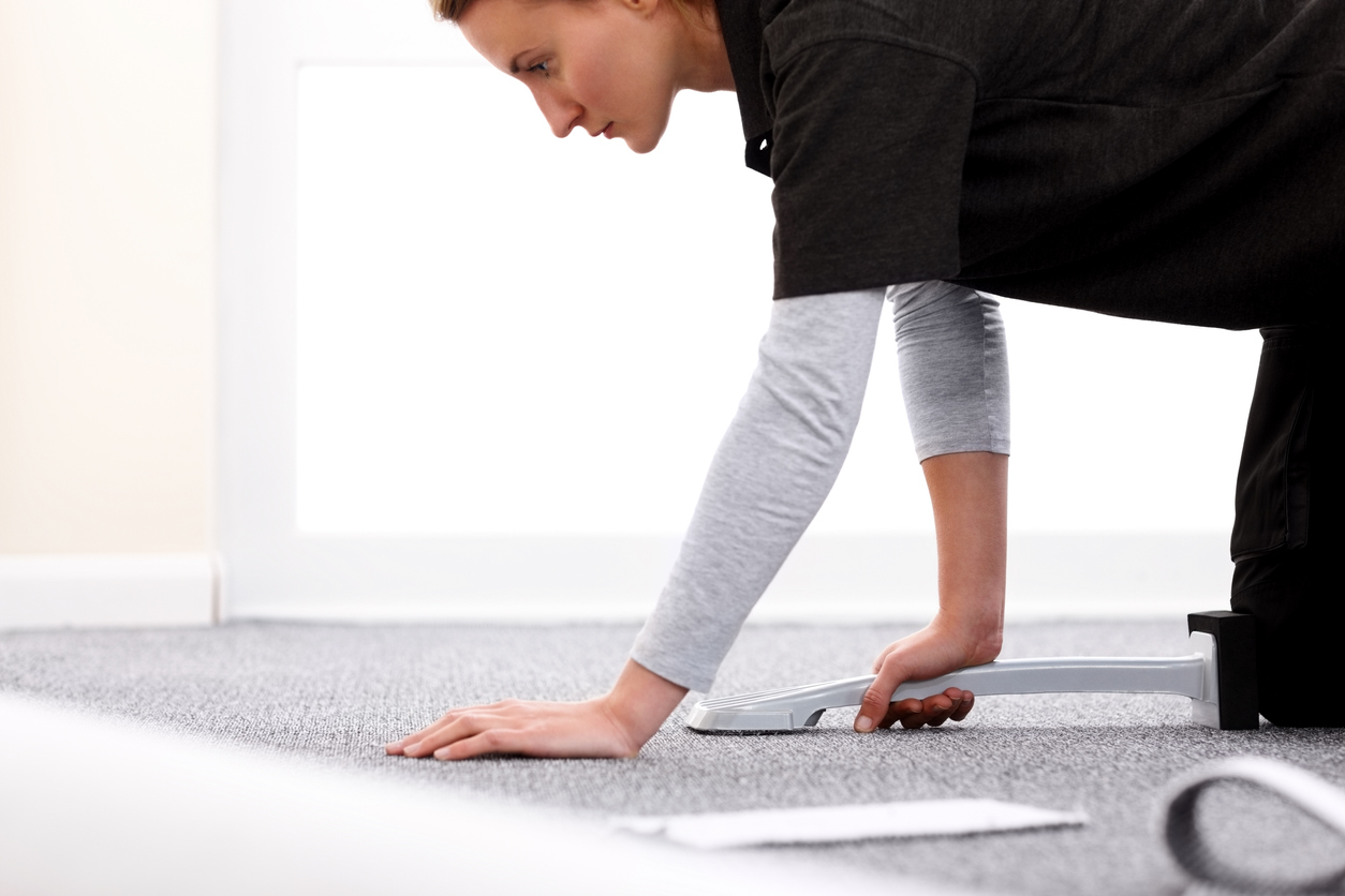 Female installer using a knee kicker to stretch carpet