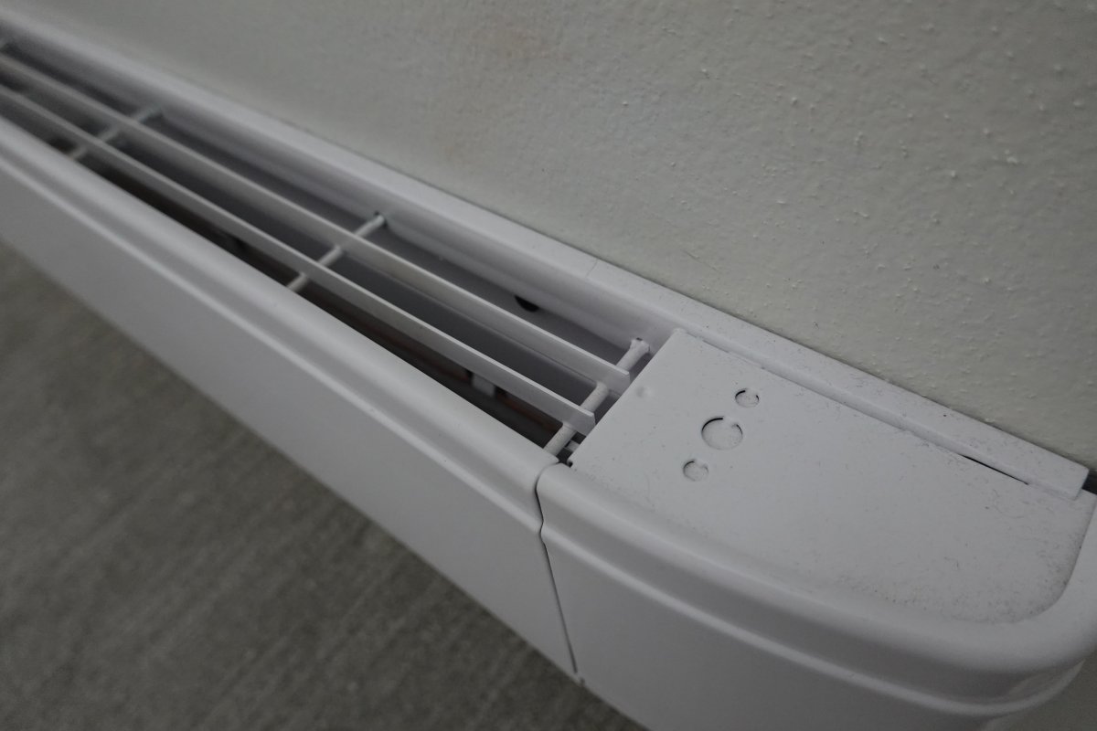 Closeup a white electric baseboard heater.