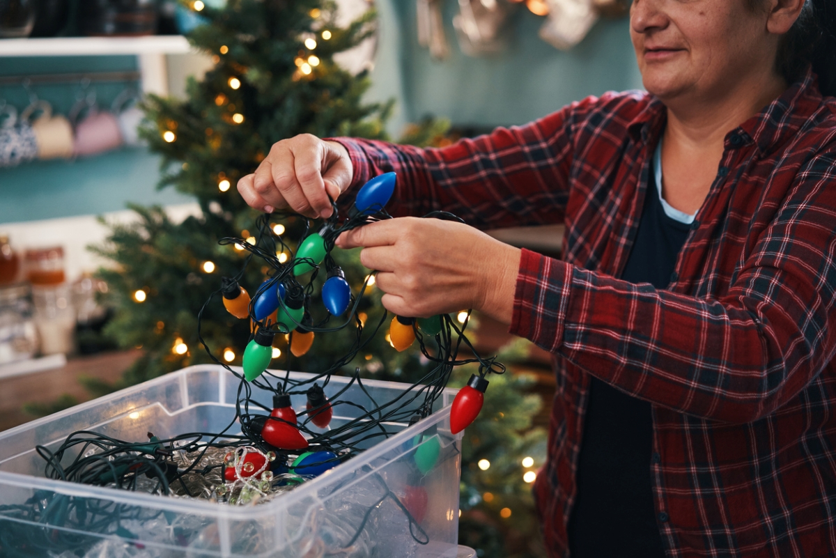 Woman unraveling Christmas lights from box.