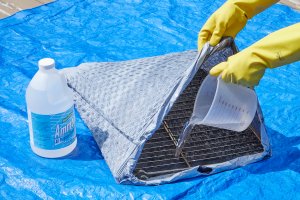 Woman adds ammonia to a trash bag with oven racks inside.