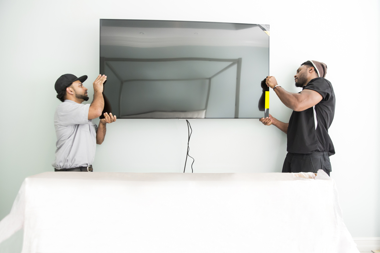 how to mount a tv on the wall two technicians work together mounting tv onto wall