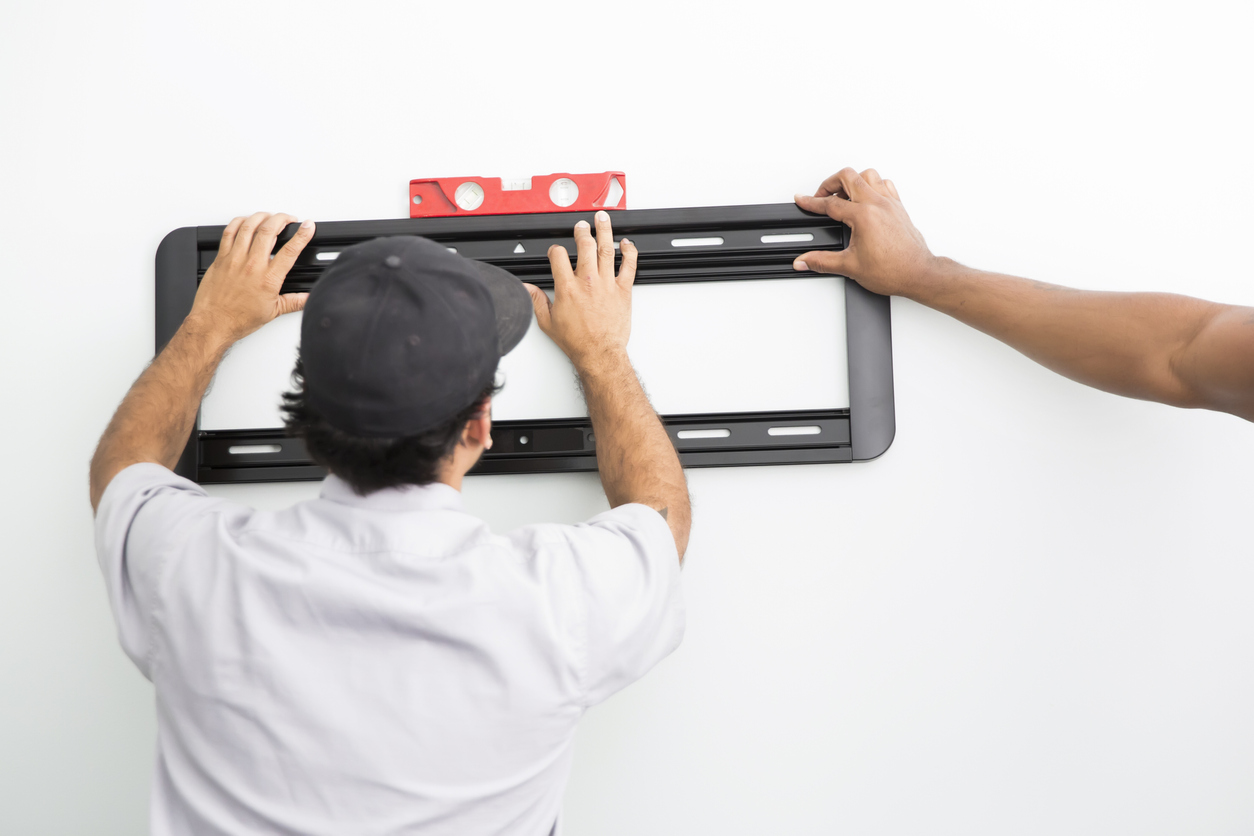 how to mount a tv on the wall technicians using level to position tv bracket on wall