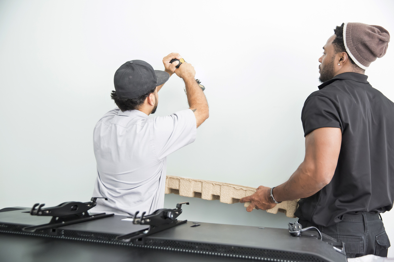 Two technicians preparing a wall on which to mount a TV.