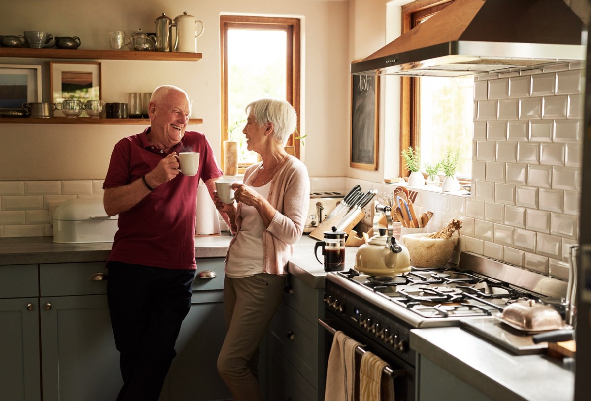 senior couple in kitchen drinking mugs of coffee together