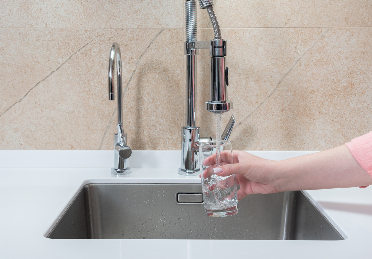 woman's hand holding cup under running water from faucet with pullout spout and lever handle