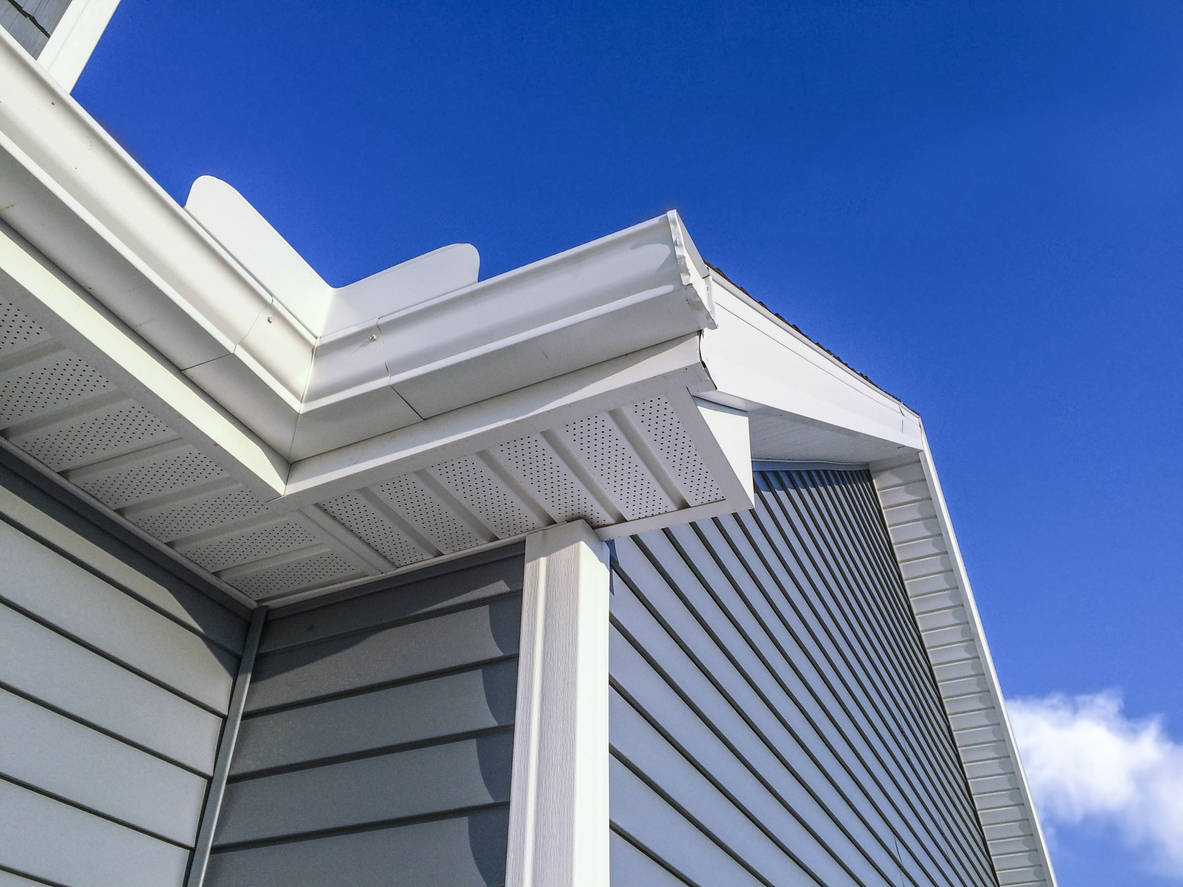low angle view of top of house with blue vinyl siding against blue sky
