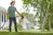 Woman wearing green shirt uses a hose-end sprayer to apply homemade fertilizer to lawn.