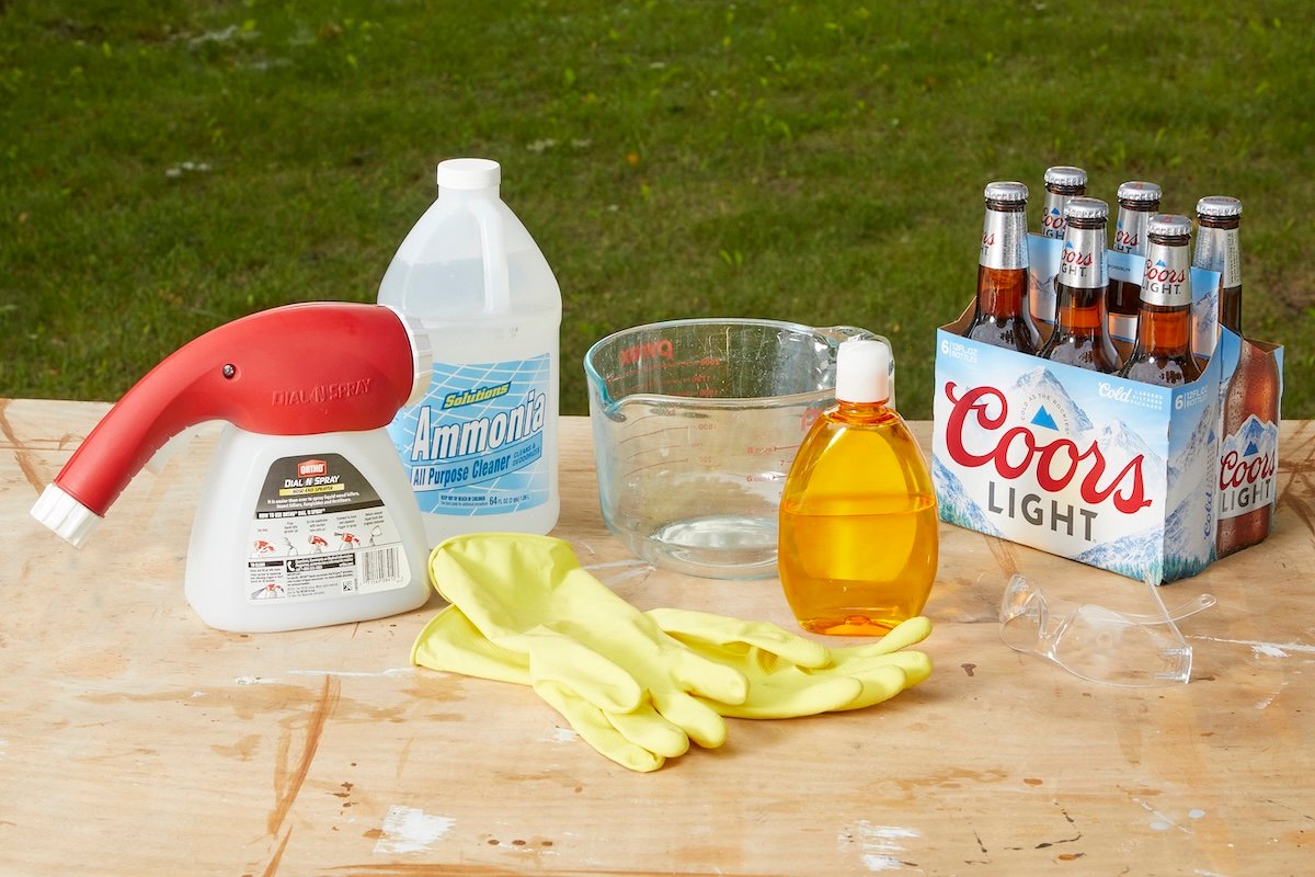 Beer, vinegar, soap and a hose-end lawn sprayer on a wood table.