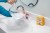 A woman pours a mixture from a large measuring cup into a large Ziploc bag on the bathroom counter.