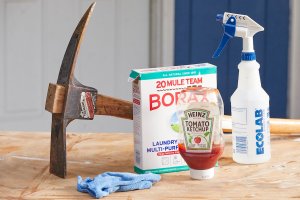 Borax, ketchup, a microfiber towel, and a rusty ax on a wood table.