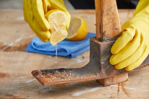 Person squeezes half a lemon on a a rusty ax blade.