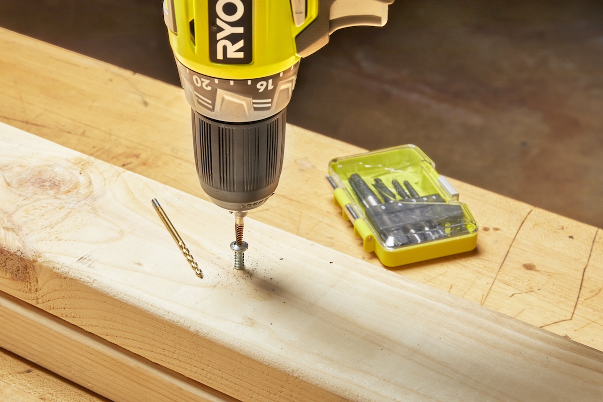 A person using a stripped screw extractor and a cordless drill/driver to remove a stripped screw in a wood stud..