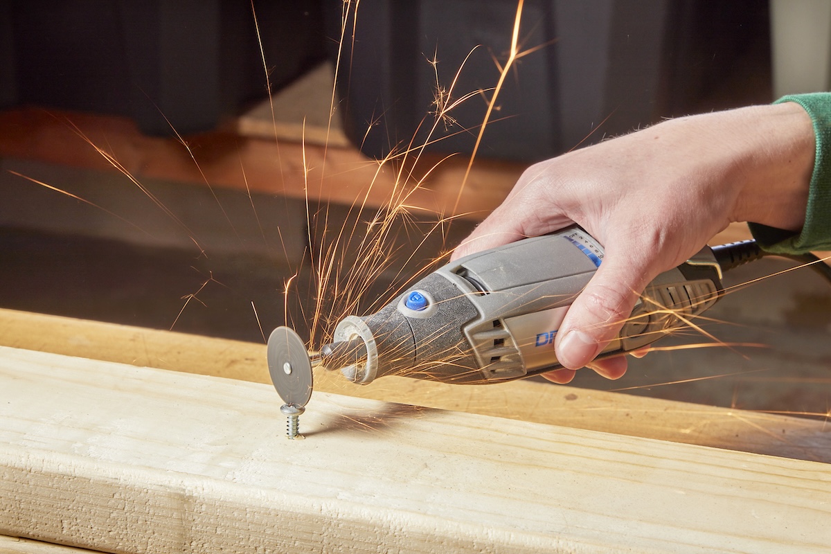 A person using an oscillating tool with a cutting wheel attachment to remove a stripped screw.