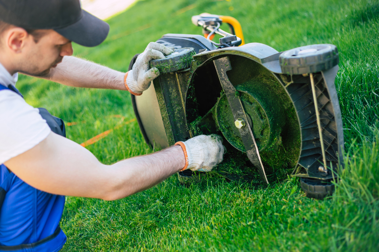A man cleans lawn mower blades.