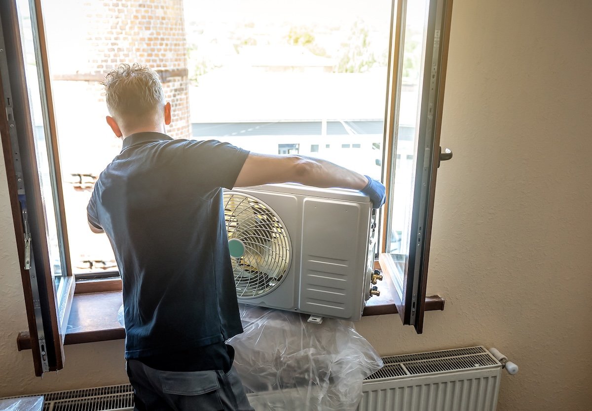 Master in black shirt is installing outer block air conditioner.