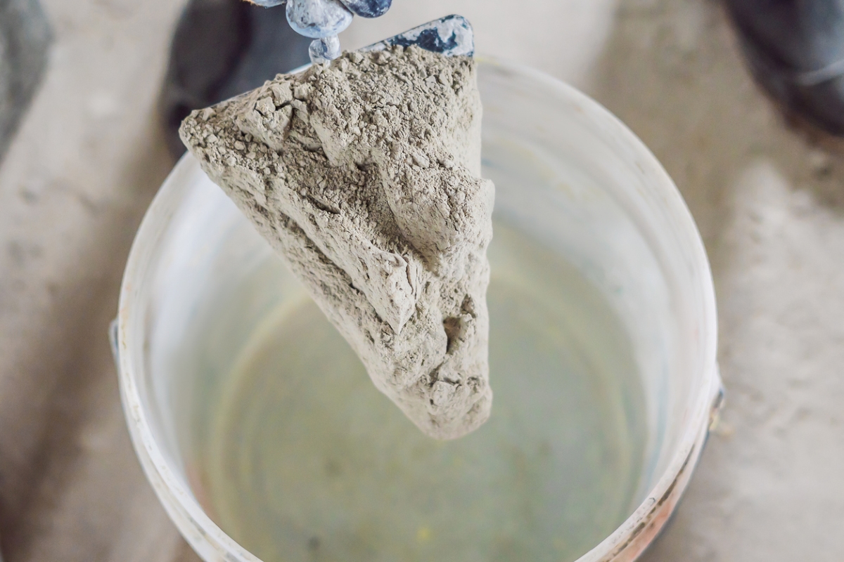 Holding dry cement over bucket.