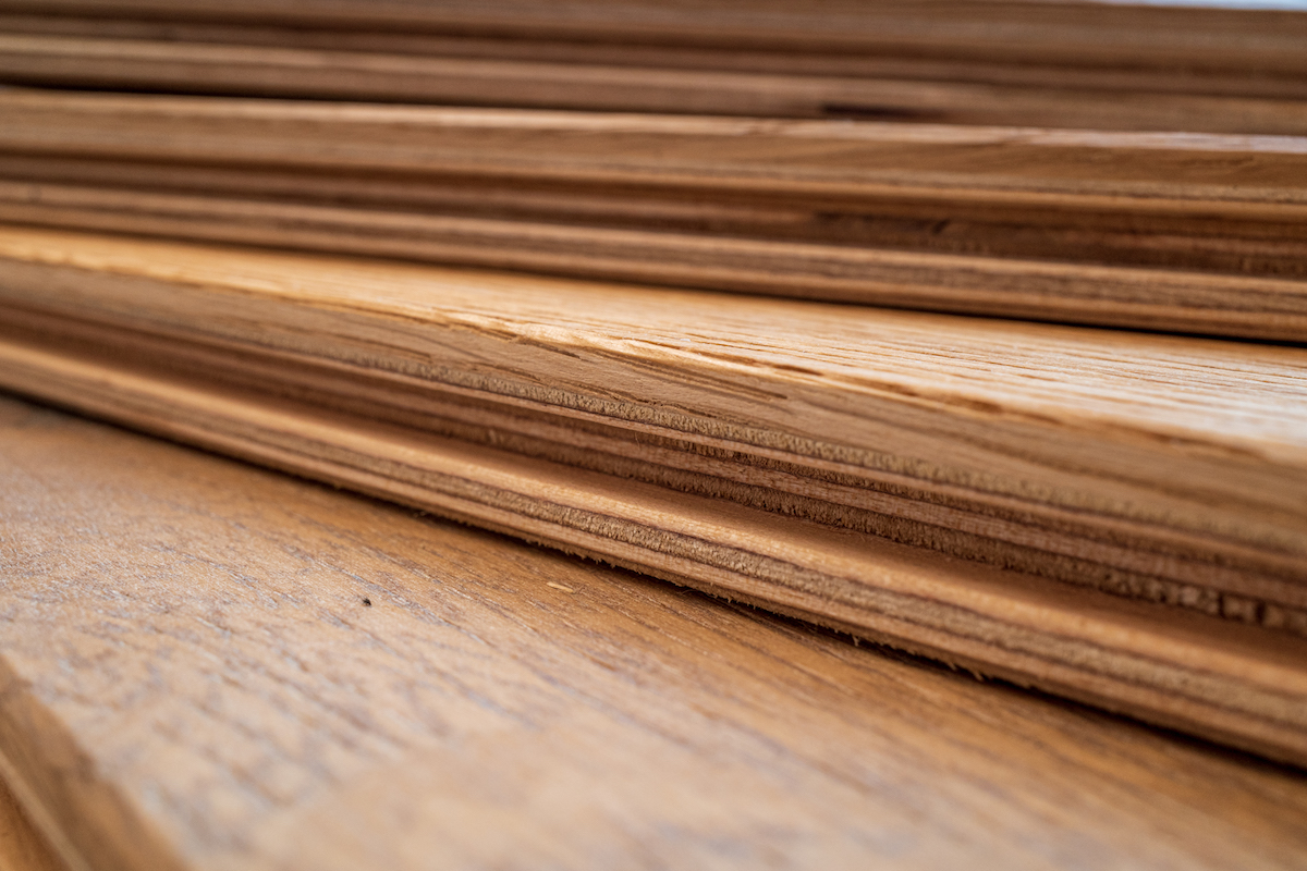 Side view of a fanned stack of light-colored engineered wood flooring.