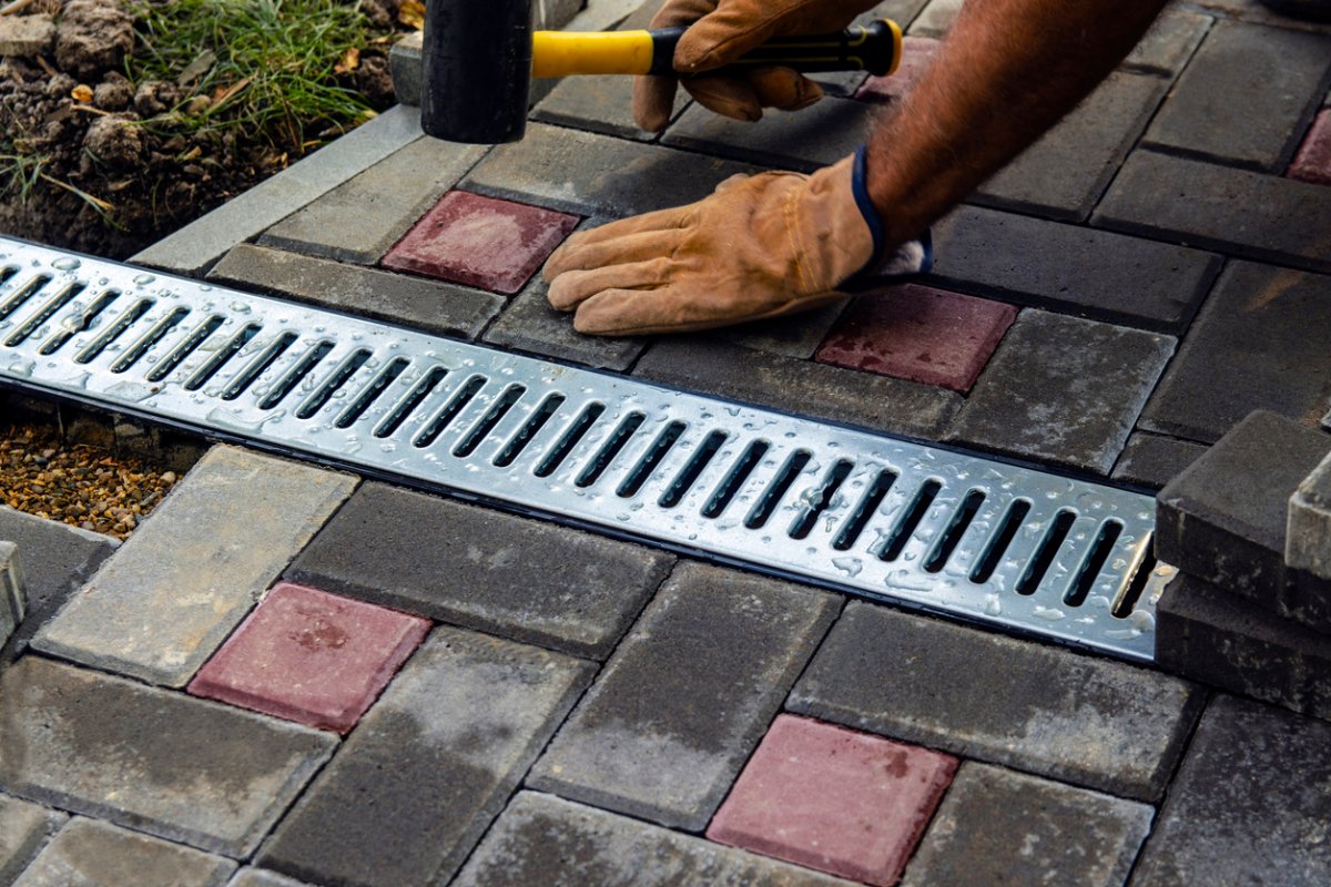 Installation of iron drainage system and paving slabs. a close-up of an iron grating along the sidewalk. Selective focus.