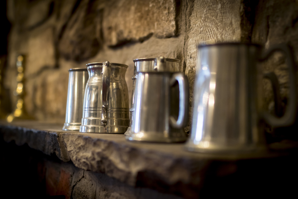 Traditional polished pewter tankard in a pub, on a stone ledge.