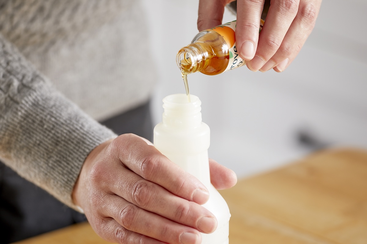 Woman pours essential oil drops into a spray bottle.