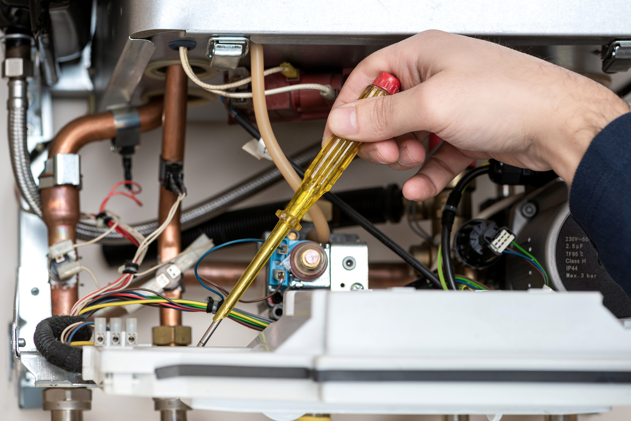 Technician repairing the combi gas boiler with Screwdriver in hand