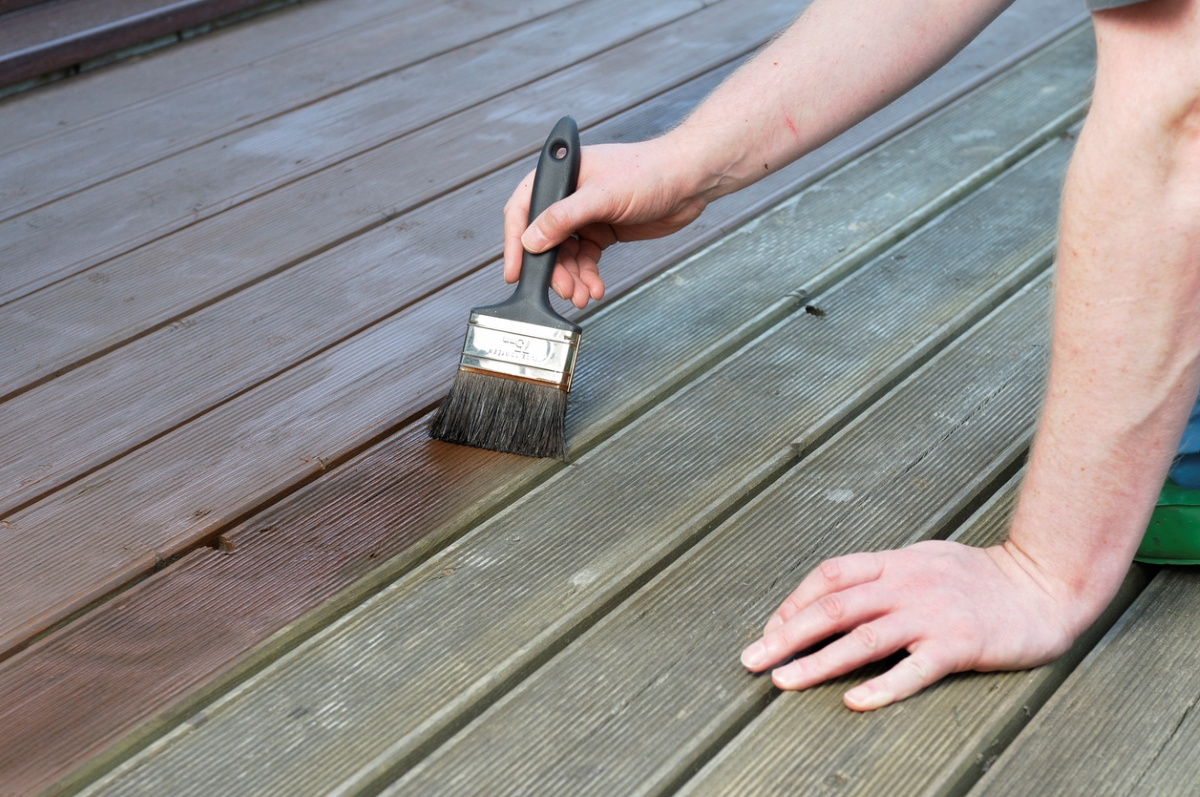painting pressure treated wood - man painting deck