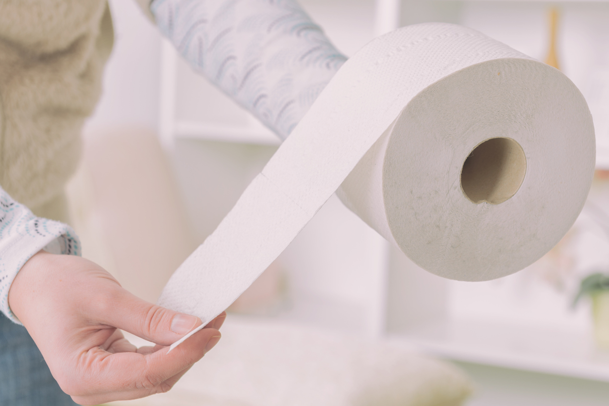woman's hand unrolling a roll of toilet paper in the bathroom