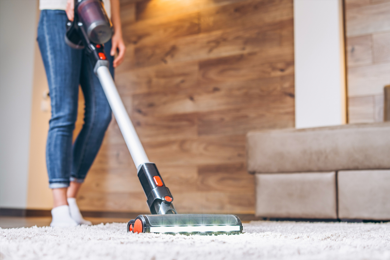 floor level view of a woman vacuuming a carpet in the living room