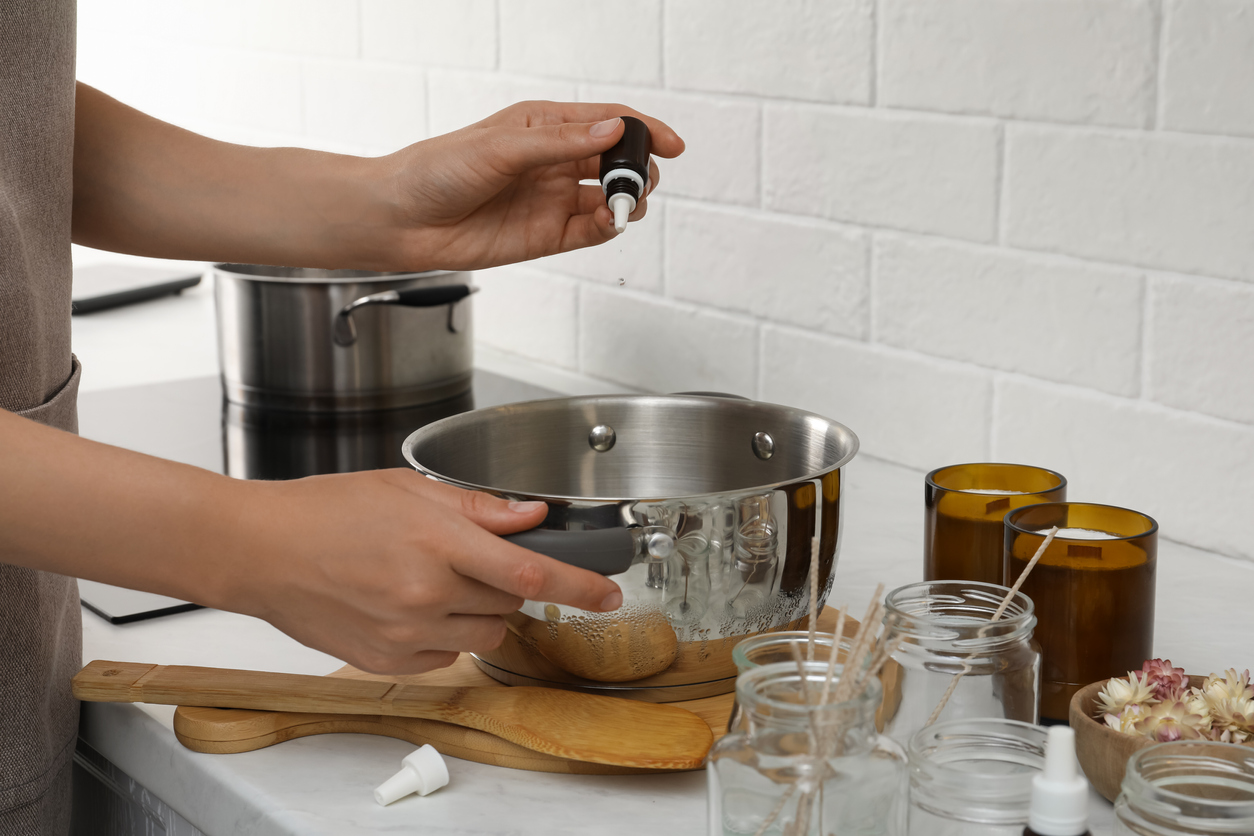 woman in the kitchen dropping essential oil into large pot to boil