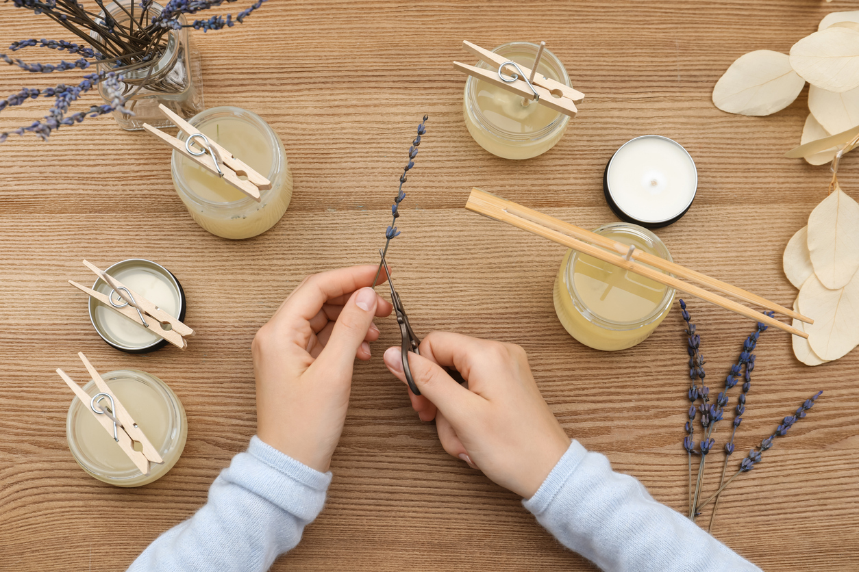 overhead view of woman's hands crafting air fresheners with candles clothespins and lavender