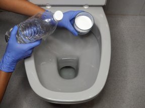 baking soda and vinegar gloved hands holding ingredients over toilet