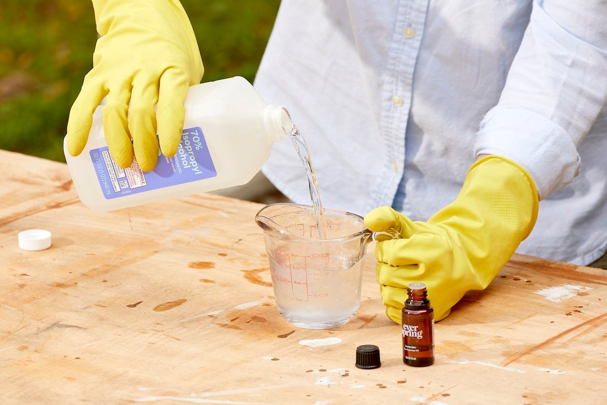 Woman pours isopropyl alcohol into a measuring cup.